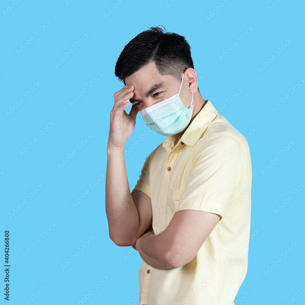Stressful COVID-19 Coronavirus portrait handsome young asian .man wearing yellow shirt and mask protection from covid 19 isolated on blue background in studio. Asian man people. COVID-19 concept. Stressful COVID-19 Coronavirus portrait handsome young asian .man wearing yellow shirt and mask protection from covid 19 isolated on blue background in studio. Asian man people. COVID-19 concept.