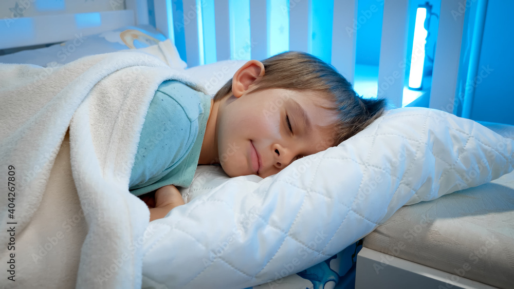 Portrait of cute toddler boy lying in bed and sleeping at night. Calm beautiful child in bed Portrait of cute toddler boy lying in bed and sleeping at night. Calm beautiful child in bed