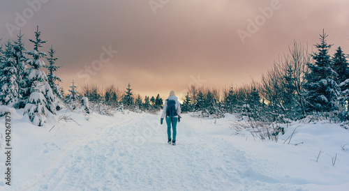 Woman hiking through winter landscape during colorful sunset