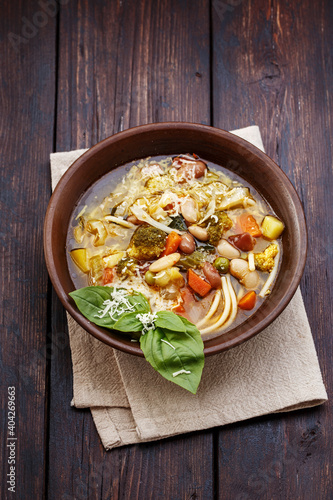 Vegetable italian minestrone soup in rustic style on old wooden table