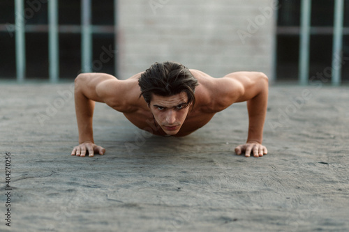 Young muscle handsome man does push-ups with naked torso.