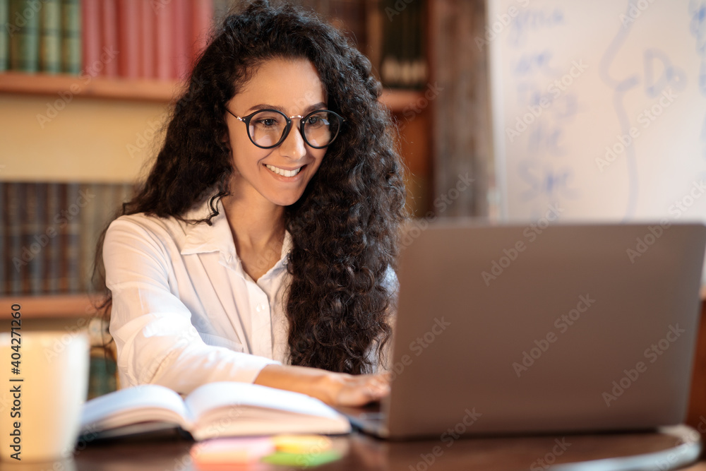 Woman in glasses sitting at desk and using laptop Woman in glasses sitting at desk and using laptop