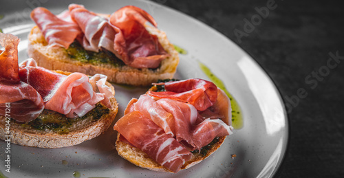 Bruschetta with prosciutto and pesto sauce on plate photo