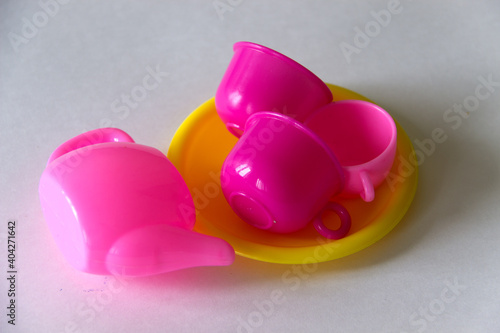 Toys for kids. Plastic tableware set. Teapot and cups on a white background.