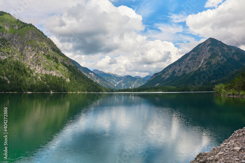 Lake Heiterwanger See in Tirol, Austria, with clouds over the mountains and their shadows on the ground. Holiday, vacation, tourism, hiking, travel destination.