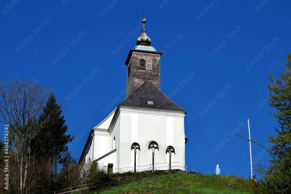 Josefikirche auf einer Anhöhe in Bad Schwanberg vor blauem Himmel (Weststeiermark)