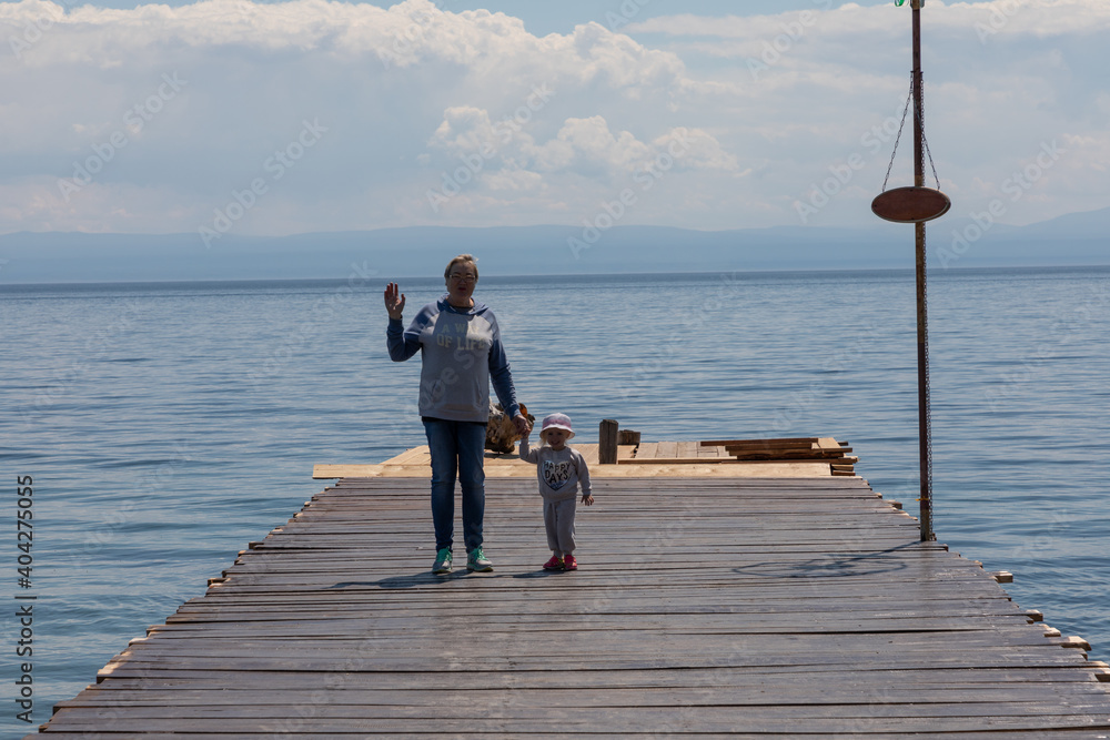 Grandmother and granddaughter walk on the pier on the lake