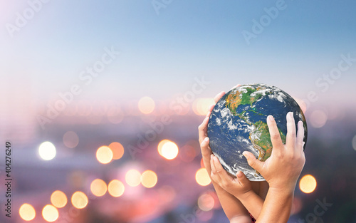 Earth Day concept: Family hands holding earth global blurred city night background. Elements of this image furnished by NASA