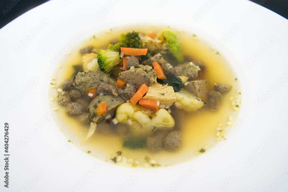 Ein weißer Teller Gemüsesuppe, Hühnersuppe mit Karotten, Leberknödel und Bio Gemüse, Produktbild