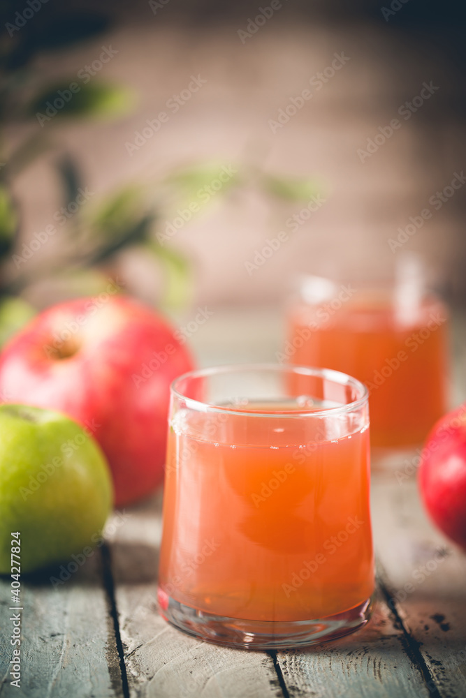 Fototapeta premium Glass of fresh apple juice and red apples on wooden background