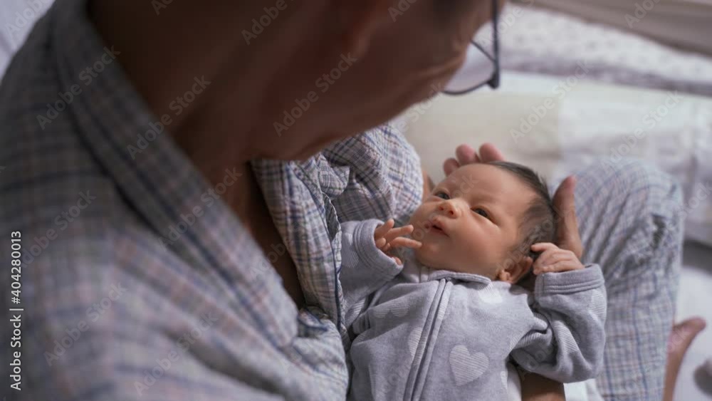 asian grandfather holding and lulling baby infant in arm. parent communication by looking. baby pay attention to listening to father. playing with innocence kid. asian grandfather holding and lulling baby infant in arm. parent communication by looking. baby pay attention to listening to father. playing with innocence kid.