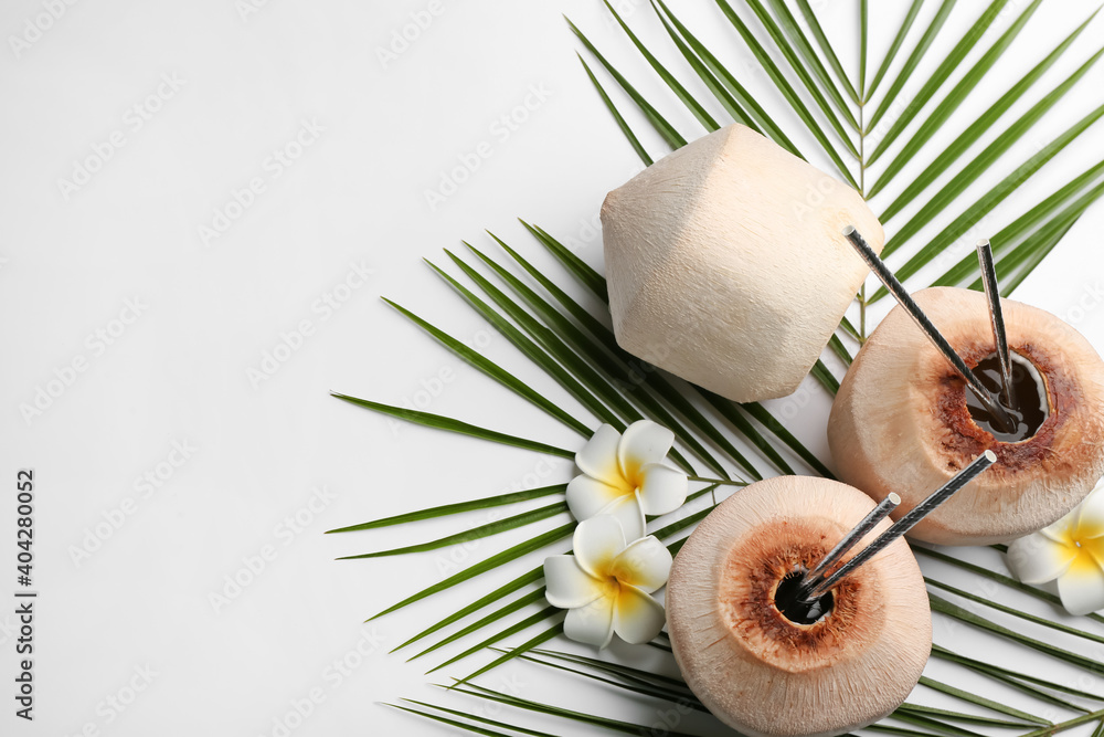 Fresh coconuts with drinking straws and flowers on white background, flat lay. Space for text Fresh coconuts with drinking straws and flowers on white background, flat lay. Space for text
