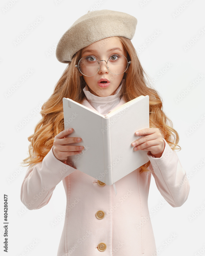 portrait of a stylish little girl in a pink coat, beret and glasses with a white book in her hands portrait of a stylish little girl in a pink coat, beret and glasses with a white book in her hands
