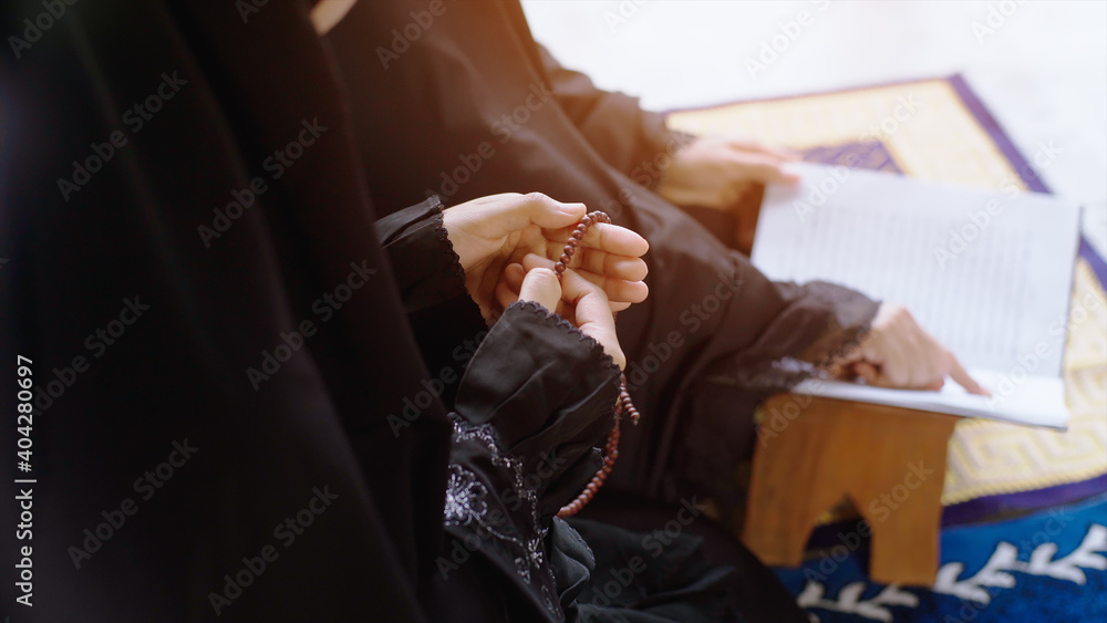 Portrait of an Asian muslim women in a daily prayer at home reciting Surah al-Fatiha passage of the Qur'an in a single act of Sujud called a Sajdah or prostration