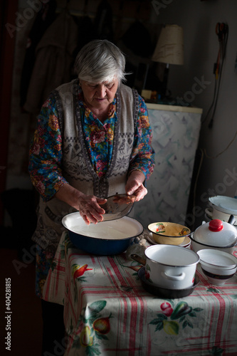 Russian grandmother washes dishes in a basin in the village