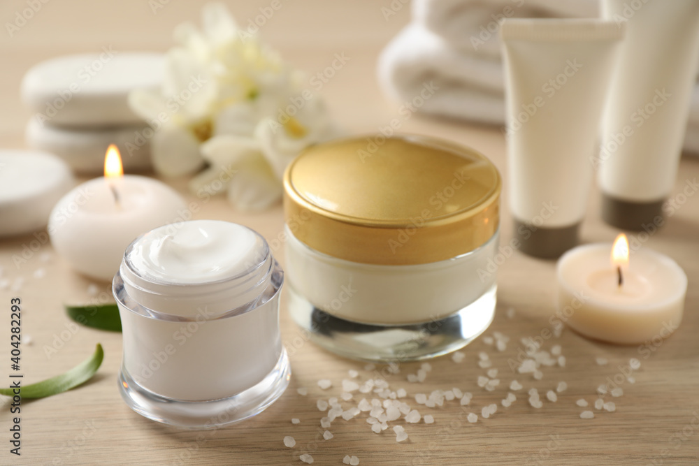 Composition with skin care products and candles on wooden table, closeup