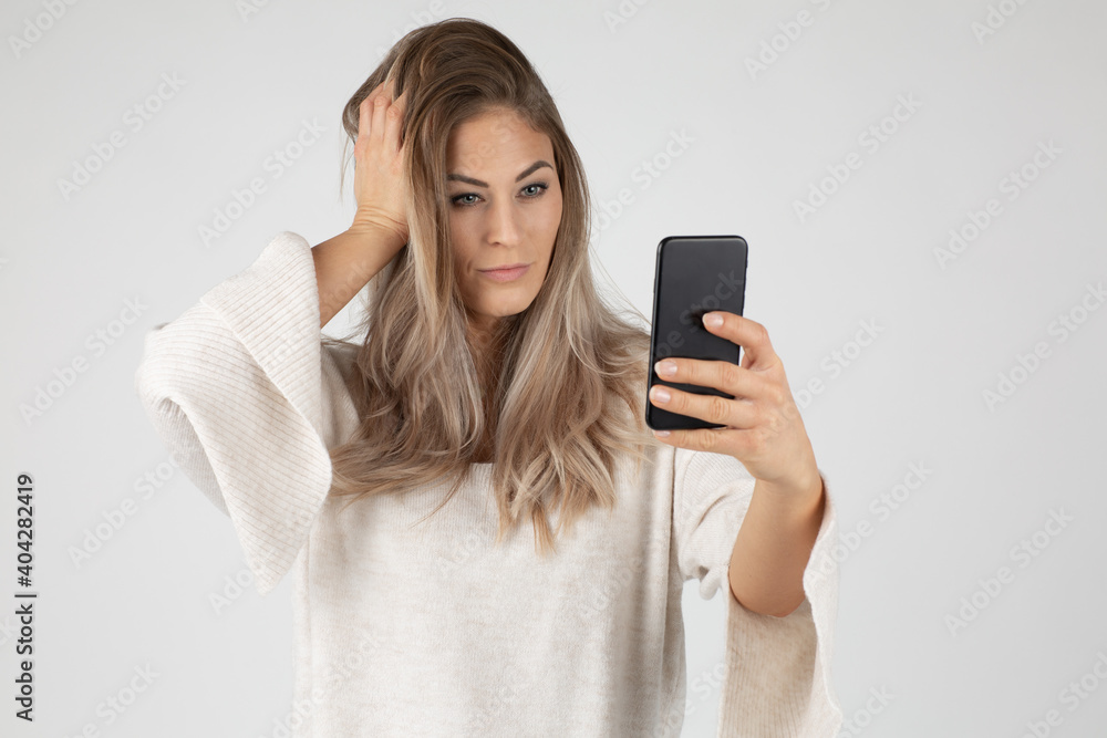 studios shot Beautiful young blond woman in casual outfit taking selfie mit mobile phone and hand in hair
studios shot Beautiful young blond woman in casual outfit taking selfie mit mobile phone and hand in hair