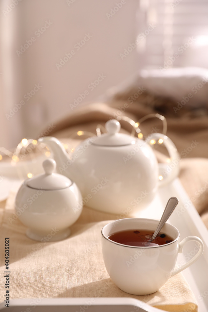 White tray with ceramic tea set on bed White tray with ceramic tea set on bed