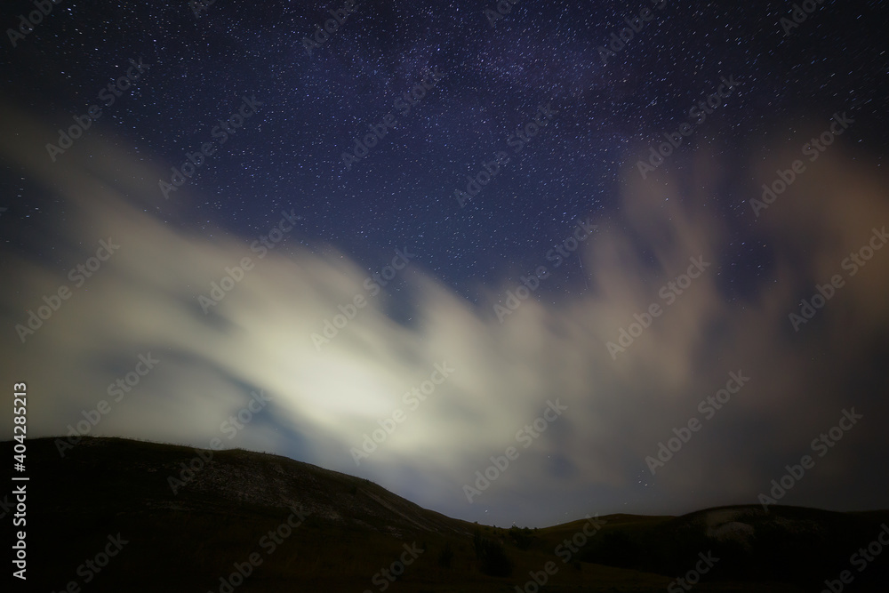 Bright stars in the night sky with clouds.