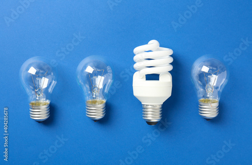 Vintage and modern lightbulbs on blue background, flat lay