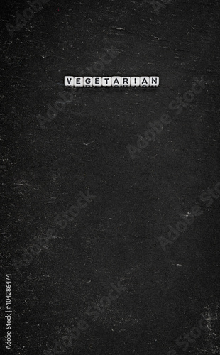 Word vegetarian on black stone background