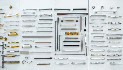 Big selection of handles cabinets parts on a white background shop window. samples of Metal and Stainless Steel handle styles on wooden kitchen cabinet with different Stainless Steel handles. photo