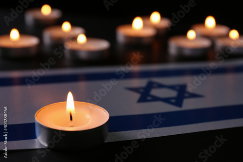 Burning candle and flag of Israel on black table. Holocaust memory day photo