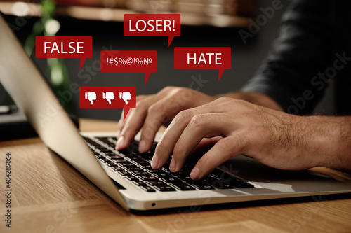 Fotografi Man using laptop and icons with offensive messages, closeup