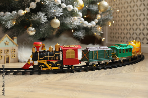 Toy train and railway near Christmas tree indoors