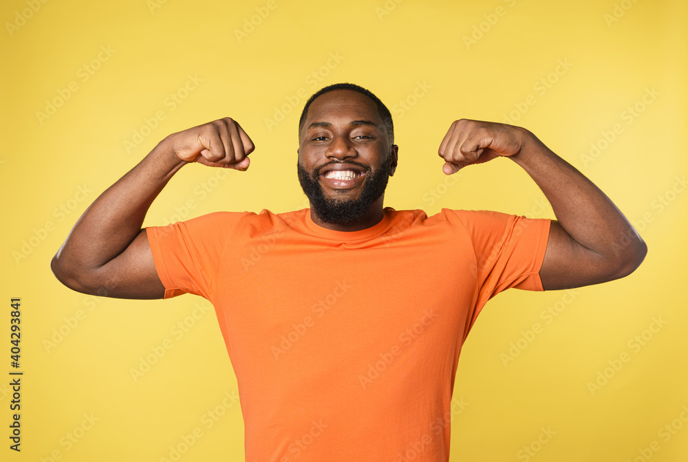 Black man thinks to have strong muscles. yellow background Black man thinks to have strong muscles. yellow background