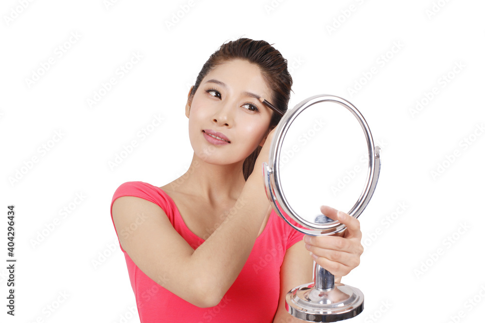 Young woman in pink dress holding a mirror,applying make-up Young woman in pink dress holding a mirror,applying make-up