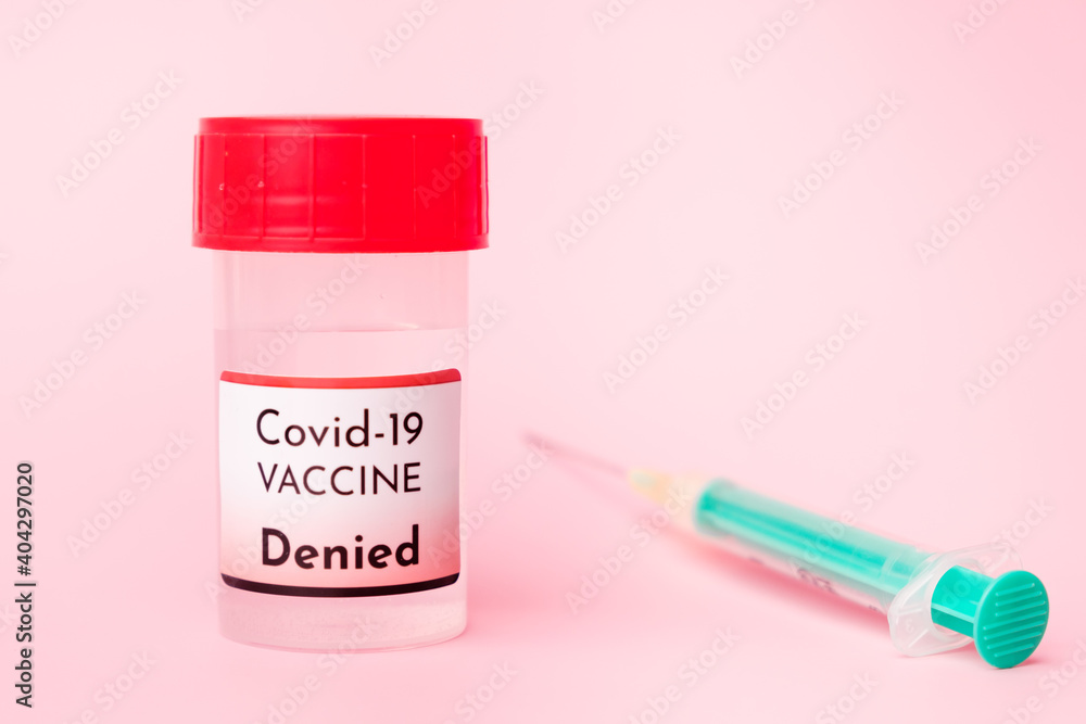 Denied Covid-19 vaccine in the bottle and disposable syringe for injection on the pink background. Prevention of coronavirus, Sars-Cov-2. Denied Covid-19 vaccine in the bottle and disposable syringe for injection on the pink background. Prevention of coronavirus, Sars-Cov-2.