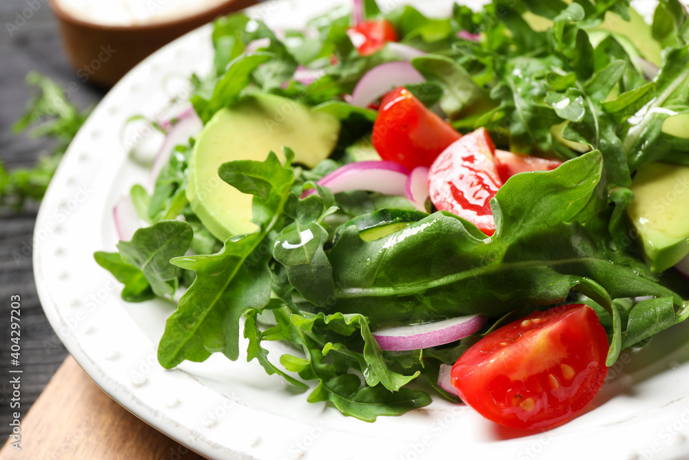 Delicious salad with avocado, arugula and tomatoes on plate, closeup Delicious salad with avocado, arugula and tomatoes on plate, closeup
