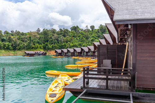 Luxury Resort with Floating Raft Houses with Kayaks on Green Lake with Tropical Trees. Traditional Thai Bungalows at Cheow Lan Lake, Ratchaprapha Dam, Khao Sok National Park in Thailand, Surat Thani