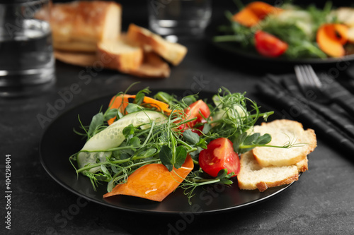 Delicious vegetable salad with microgreen served on black table