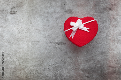 Caja de regalo con forma de corazón y lazo blanco con fondo gris photo