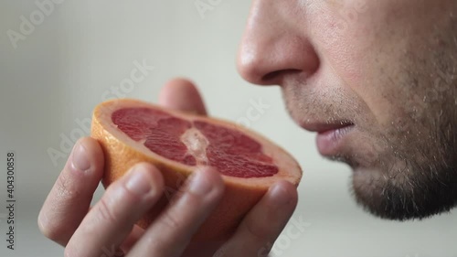 Close up of sick man trying to sense smell of half fresh grapefruit, has symptoms of Covid-19, corona virus infection - loss of smell and taste. One of the main signs of the disease.  photo