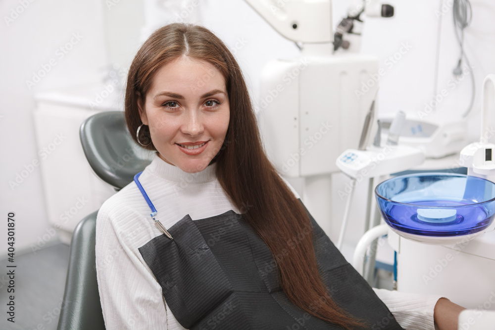 Beautiful woman smiling to the camera, sitting in dental chair