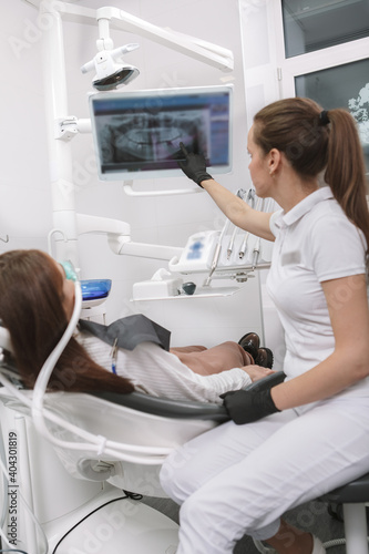 Vertical shot of a dentist explaining her patient dental x-ray scan on the screen  waiting for inhalation sedation to work