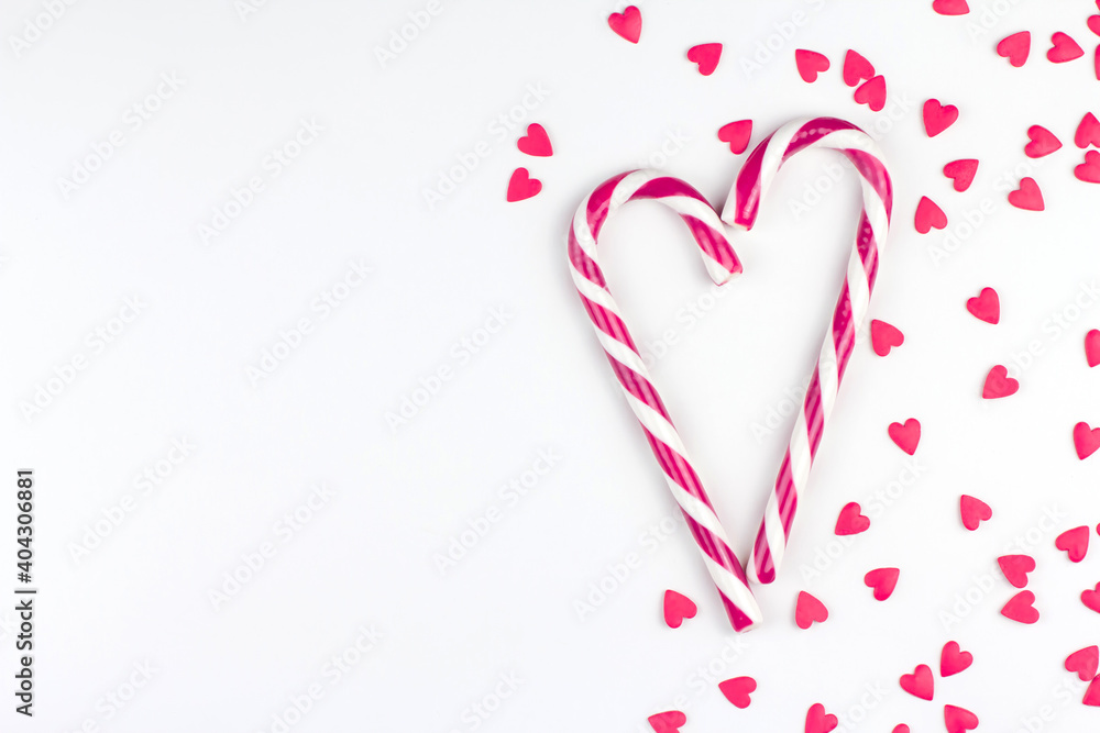 Red or pink confectionery confetti in the shape of hearts and candy canes on a white background copy space
