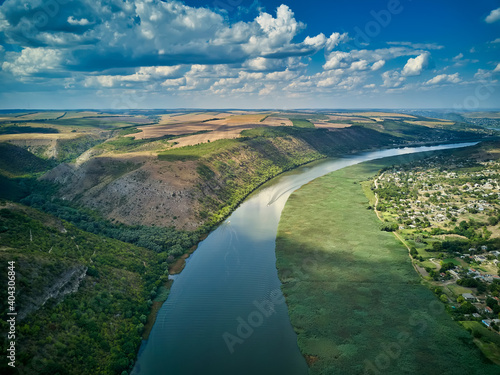 Flight through majestic river Dnister, lush green forest and village. Moldova, Europe. Landscape photography. © Igor Syrbu
