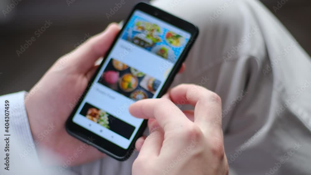 Customer selects food on online food delivery website using smartphone close-up Customer selects food on online food delivery website using smartphone close-up