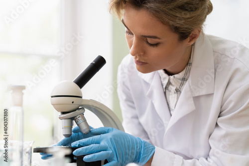 Woman scientist is using microscope in a laboratory during research