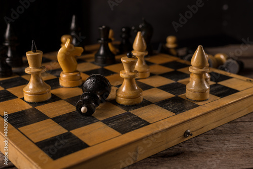 Wooden Chess Pieces on the old Chessboard against dark background.
