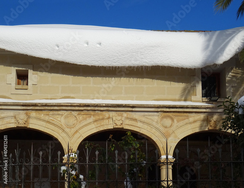 Renaissance arcade of the church of Azuqueca de Henares with snow on the roof during winter. Spain.