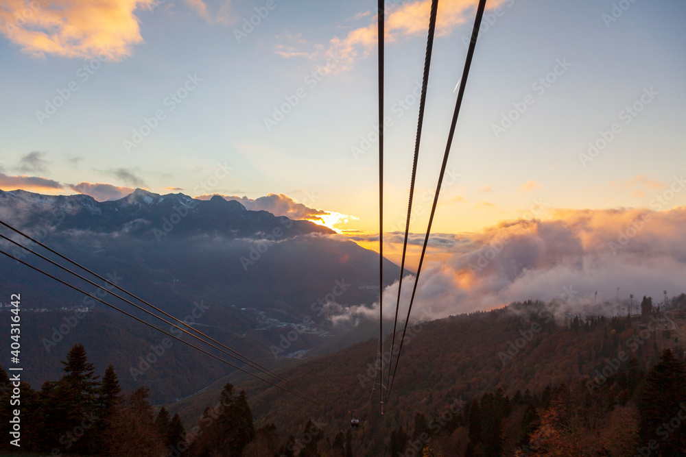 Krasnaya Polyana, Sochi, the mountains of the North Caucasus, snow-capped peaks against the background of autumn trees, red sunset over Krasnaya Polyana by cable car