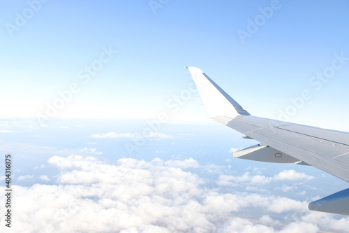 Beautiful horizon blue sky with white wing of airplane fiying above white clouds. View from airplane window