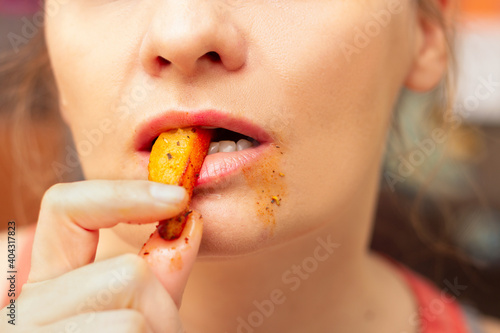 Woman putting french fries in her mouth and taking a bite  messy around the mouth 