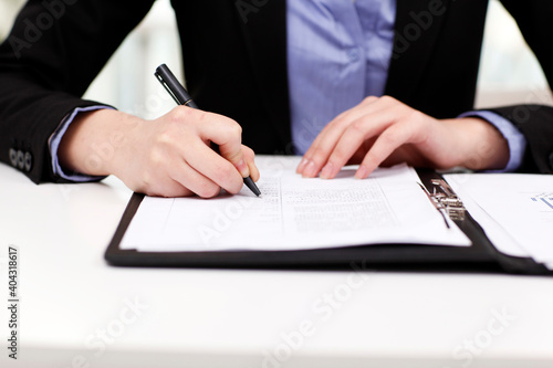 Close-up of a businesswoman's hands writing on portfolio