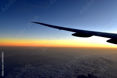Silhouette of Airplan wing in twilight sky, with beautiful light from dramatic sunset, Romantic view from airplane window.